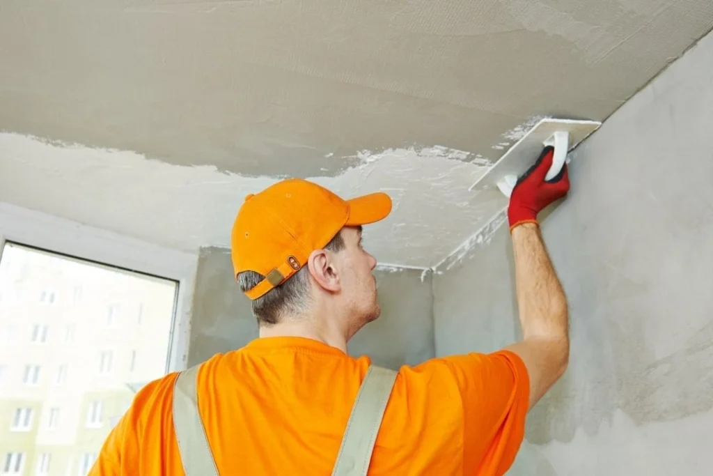 Plasterer plastering a ceiling to wall connection
